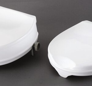 two white raised toilet seats with lids